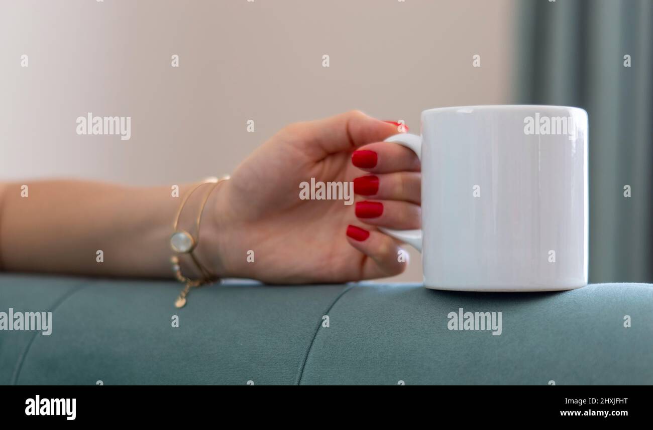 Cup. Mug Mockup. A single white sublimation printable mug and woman hand. Unbranded mug image available to all mug sellers and mug designer. Stock Photo