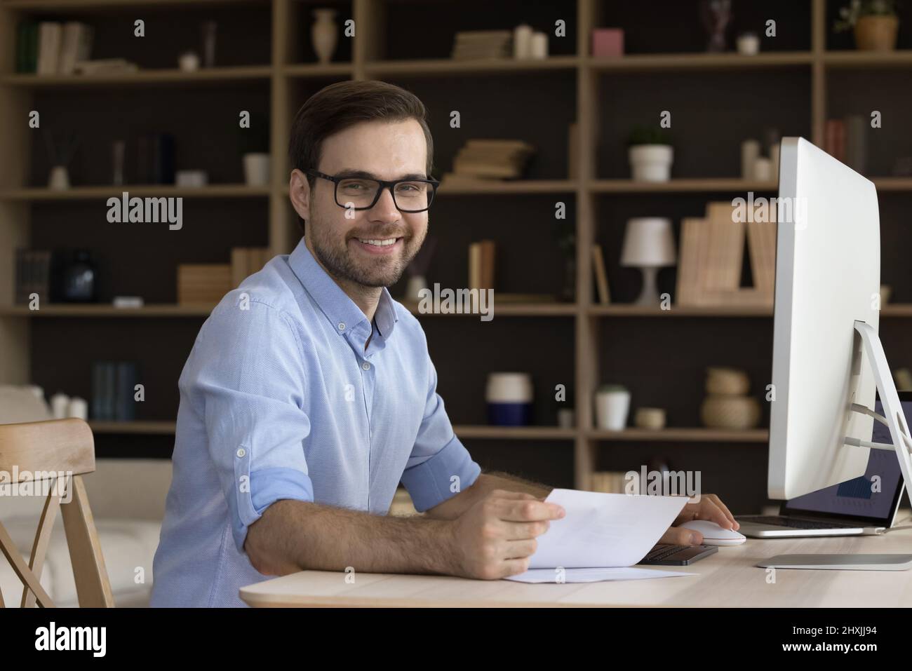 Business portrait smiling young manager sitting by computer at workplace Stock Photo