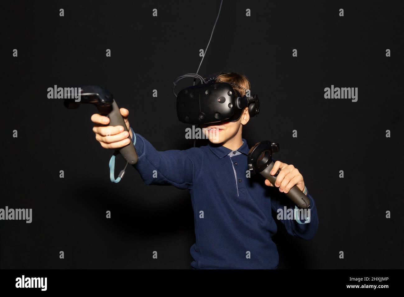 Eight years boy wearing VR headset, holding controllers in hands and