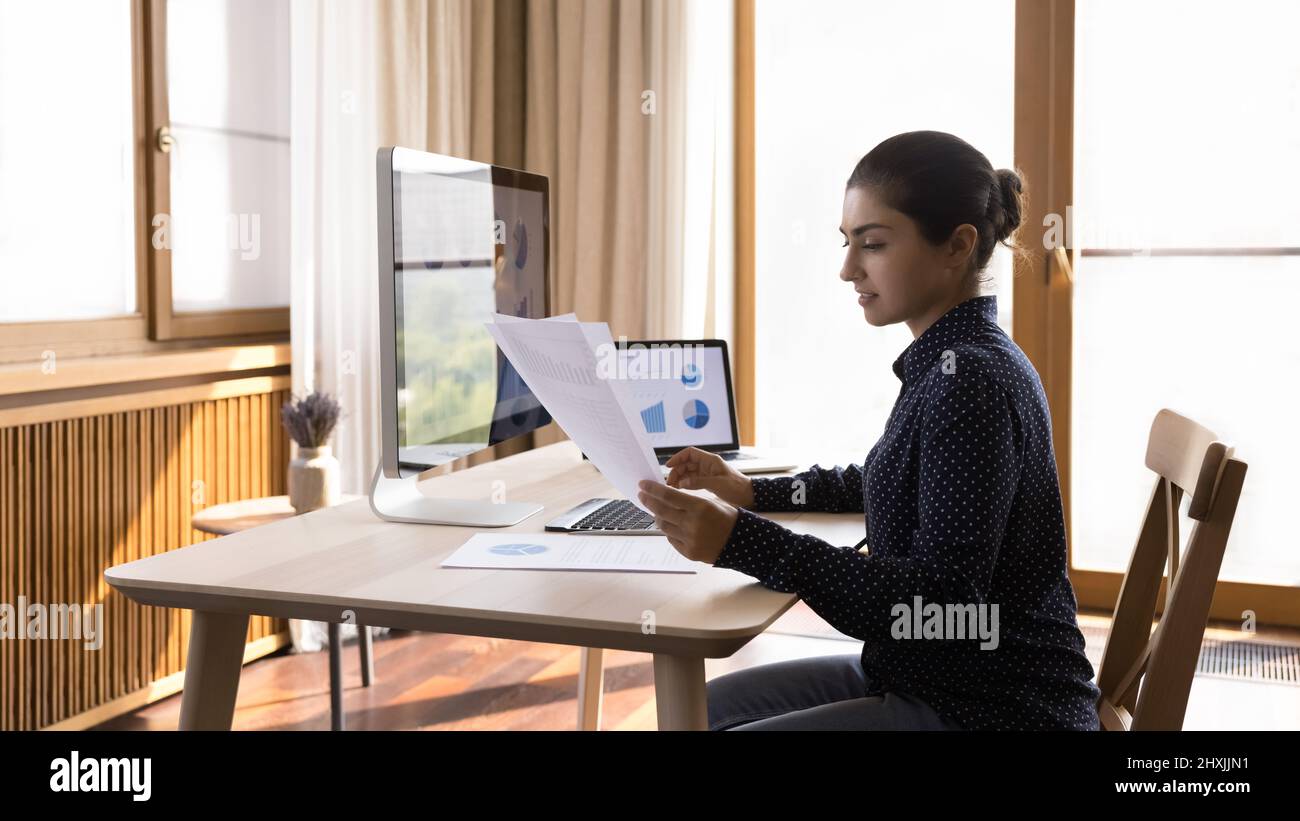 Young lady study data in report and on computer screens Stock Photo