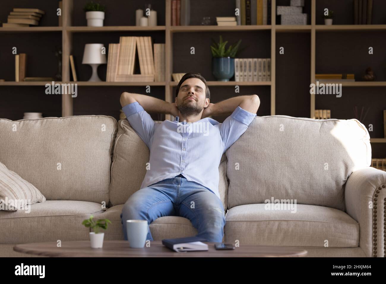 Peaceful millennial guy dream relax on couch at living room Stock Photo
