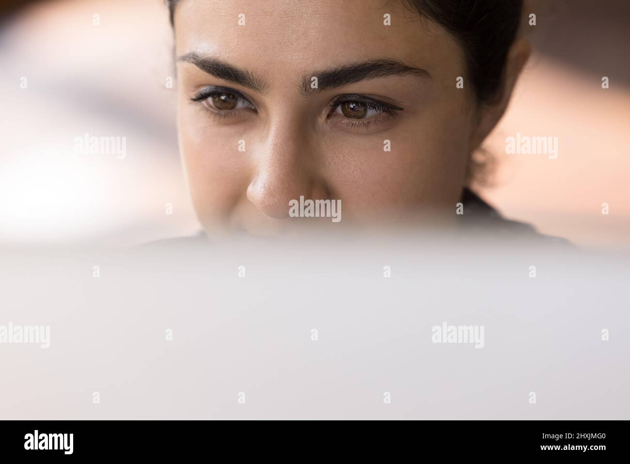 Closeup face thoughtful millennial Indian woman employee above computer screen Stock Photo