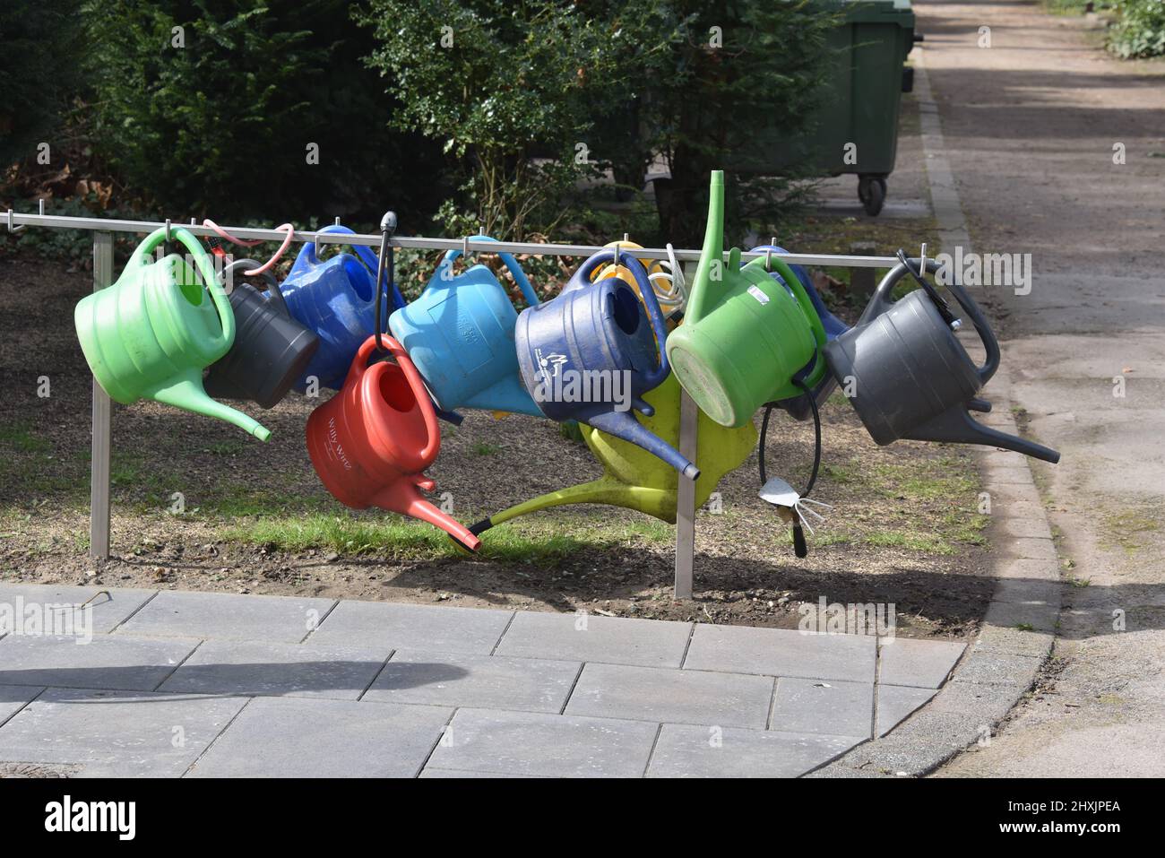12 March 2022, North Rhine-Westphalia, Cologne: Colorful plastic watering cans hang on a stand at Melaten Cemetery and can be borrowed. Photo: Horst Galuschka/dpa Stock Photo