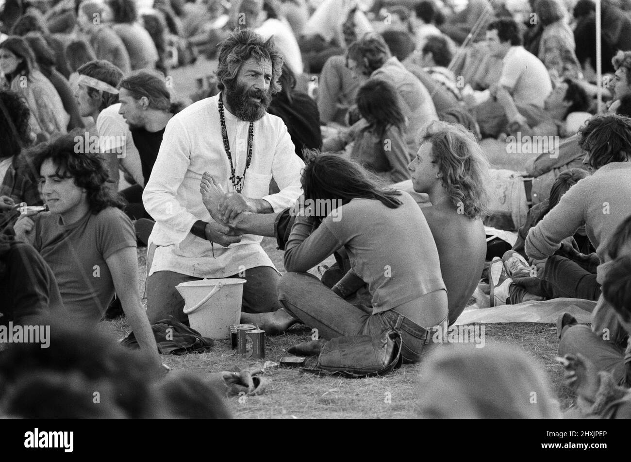 'Mick the Vic', who is the Rev Michael Scott, Vicar at St Mark's Church, Reading, tours the festival site at reading, washing the feet of pop fans. 27th August 1976. Stock Photo