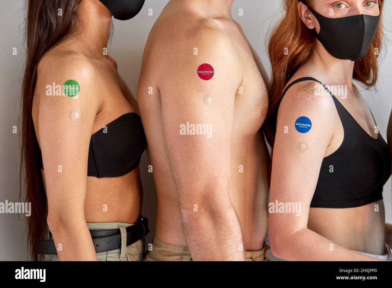 Diverse group of cropped people showing COVID-19 vaccine stickers on arms. vaccinated youth stand in row after vaccination, global immunization concep Stock Photo