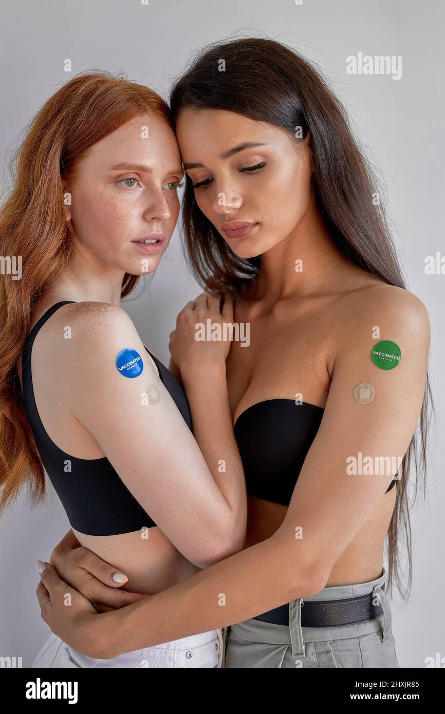two caucasian ladies showing COVID-19 vaccine on arm in concept of coronavirus vaccination program to vaccinate citizen. attractive women with long ha Stock Photo