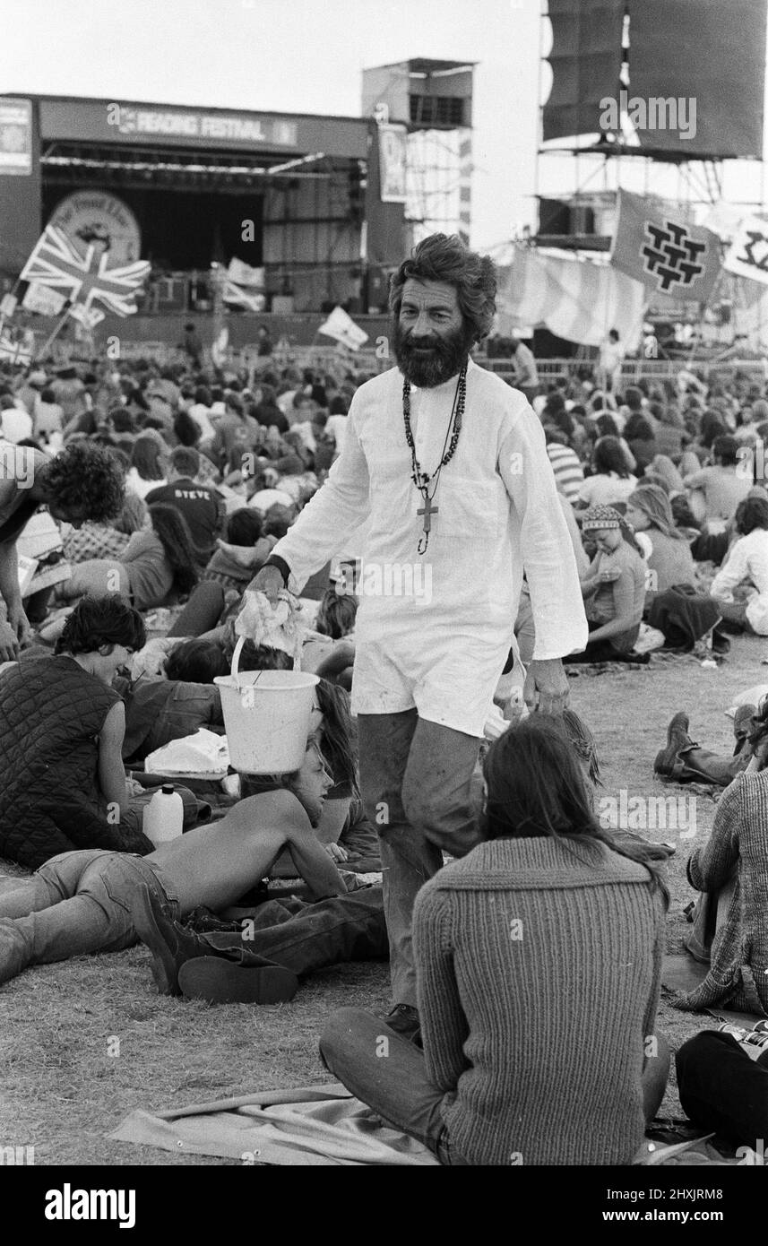 'Mick the Vic', who is the Rev Michael Scott, Vicar at St Mark's Church, Reading, tours the festival site at reading, washing the feet of pop fans. 27th August 1976. Stock Photo