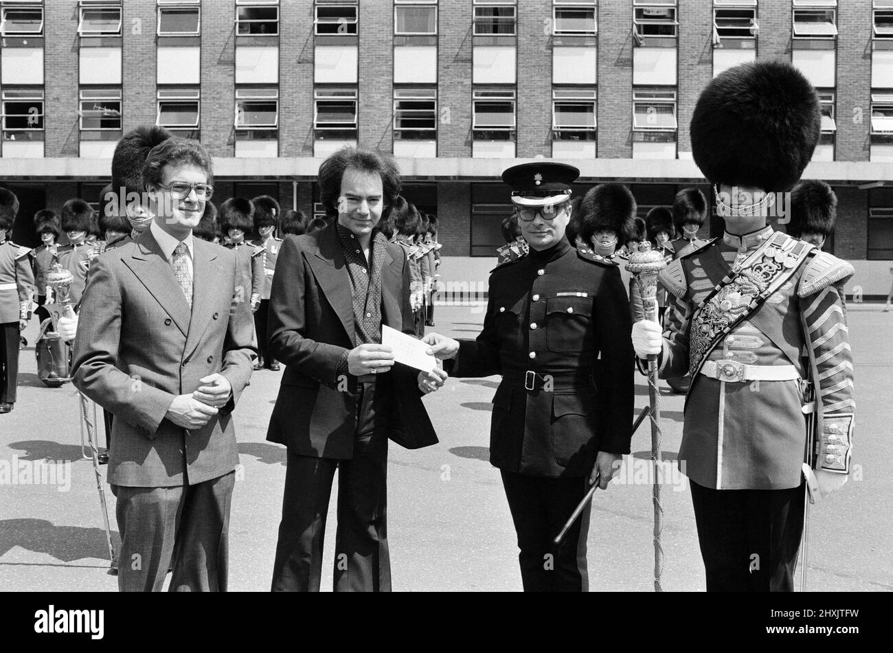 Entertainer Neil Diamond and Lord Tavistock present a cheque to the 2nd Battalion, Grenadier Guards, at Chelsea Barracks. The cheque was a 'thank you' for the Drums Corps' performance at the beginning of last Saturday's concert at Woburn Abbey when Diamond played to more than 51,000 people. It will be given to the Household Division Funds (Silver Jubilee Appeal), and is the proceeds from the sales of Neil Diamond programmes at the concert. 7th July 1977. Stock Photo