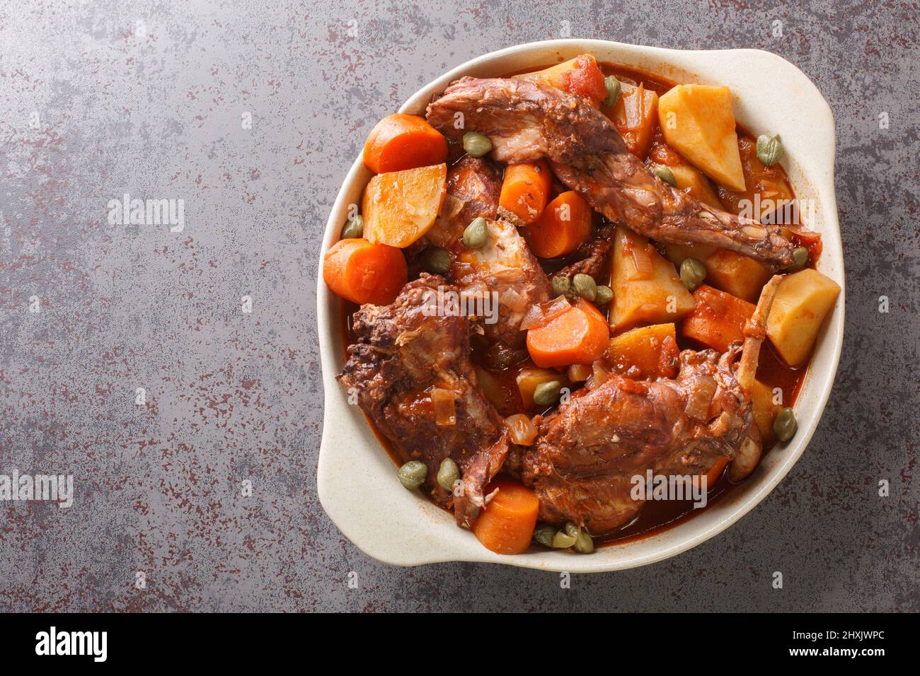 Fenkata dish of national Maltese cuisine cooked from rabbit meat with vegetables and gravy close-up in a saucepan on the table. horizontal top view fr Stock Photo