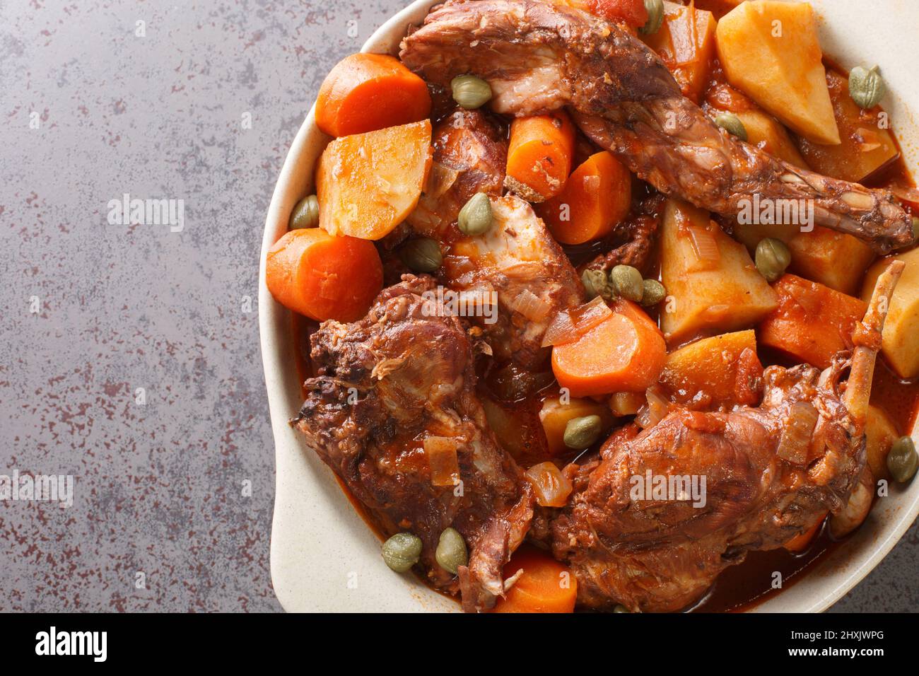 Rabbit Stew Maltese style or Stuffat tal-Fenek closeup in the pan on the table. Horizontal top view from above Stock Photo
