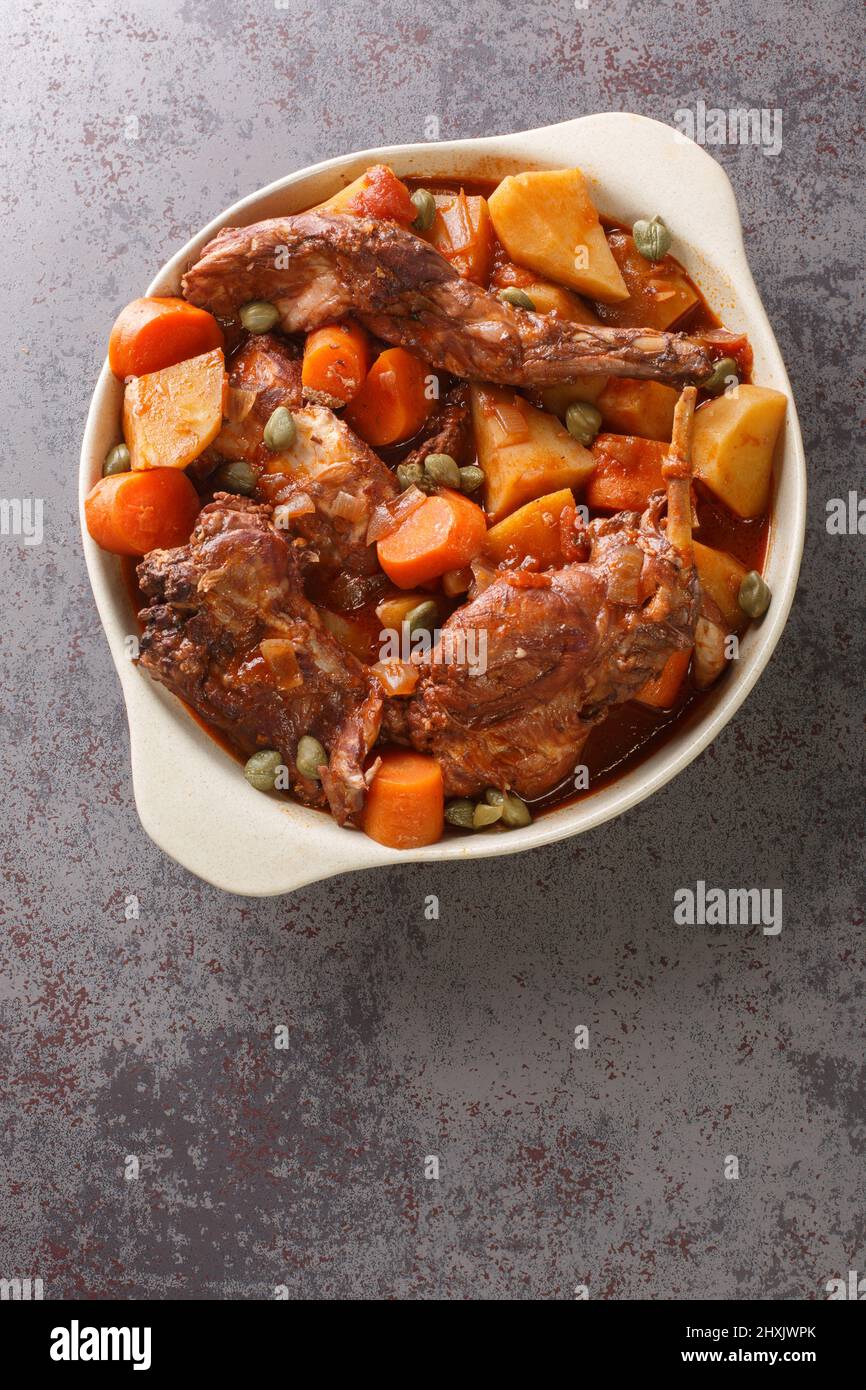 Traditional Malta national dish stewed rabbit Stuffat tal-Fenek closeup in the pan on the table. Vertical top view from above Stock Photo