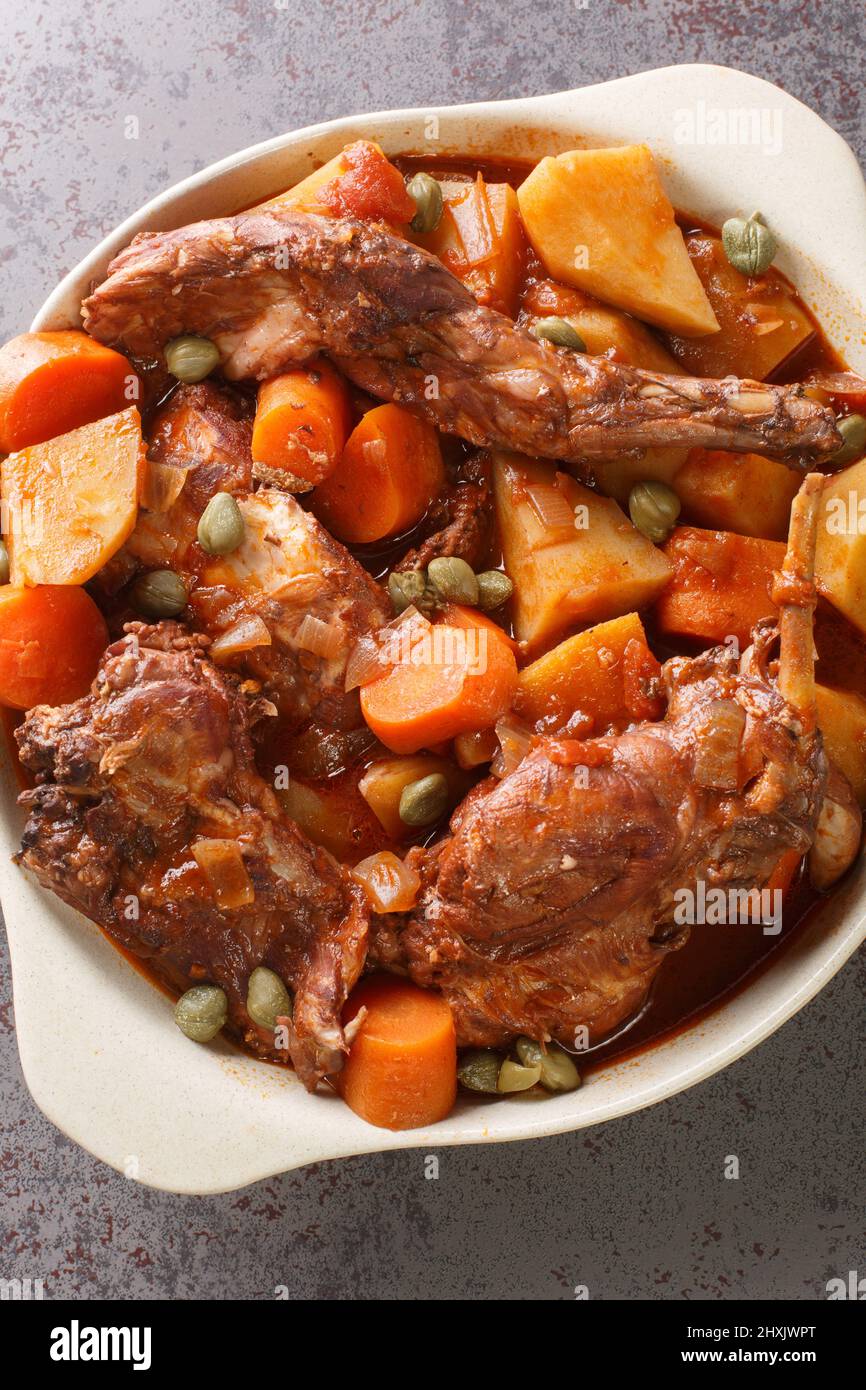 Fenkata is the national dish of Malta, a communal meal that is prepared with rabbit as the star of the feast closeup in the pan on the table. Vertical Stock Photo