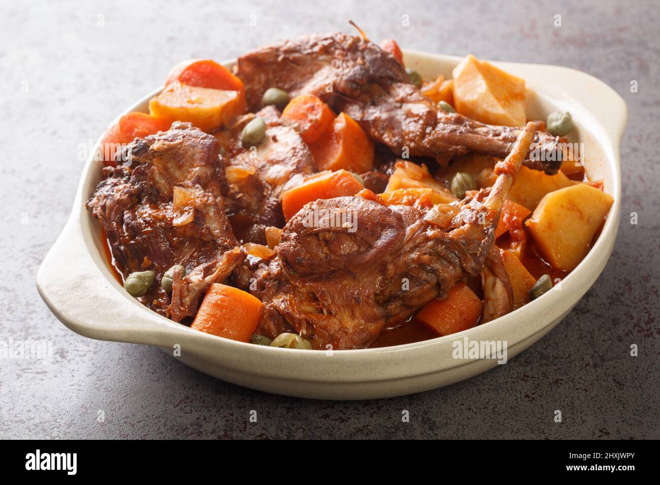 Rabbit Stew Maltese style or Stuffat tal-Fenek closeup in the pan on the table. Horizontal Stock Photo