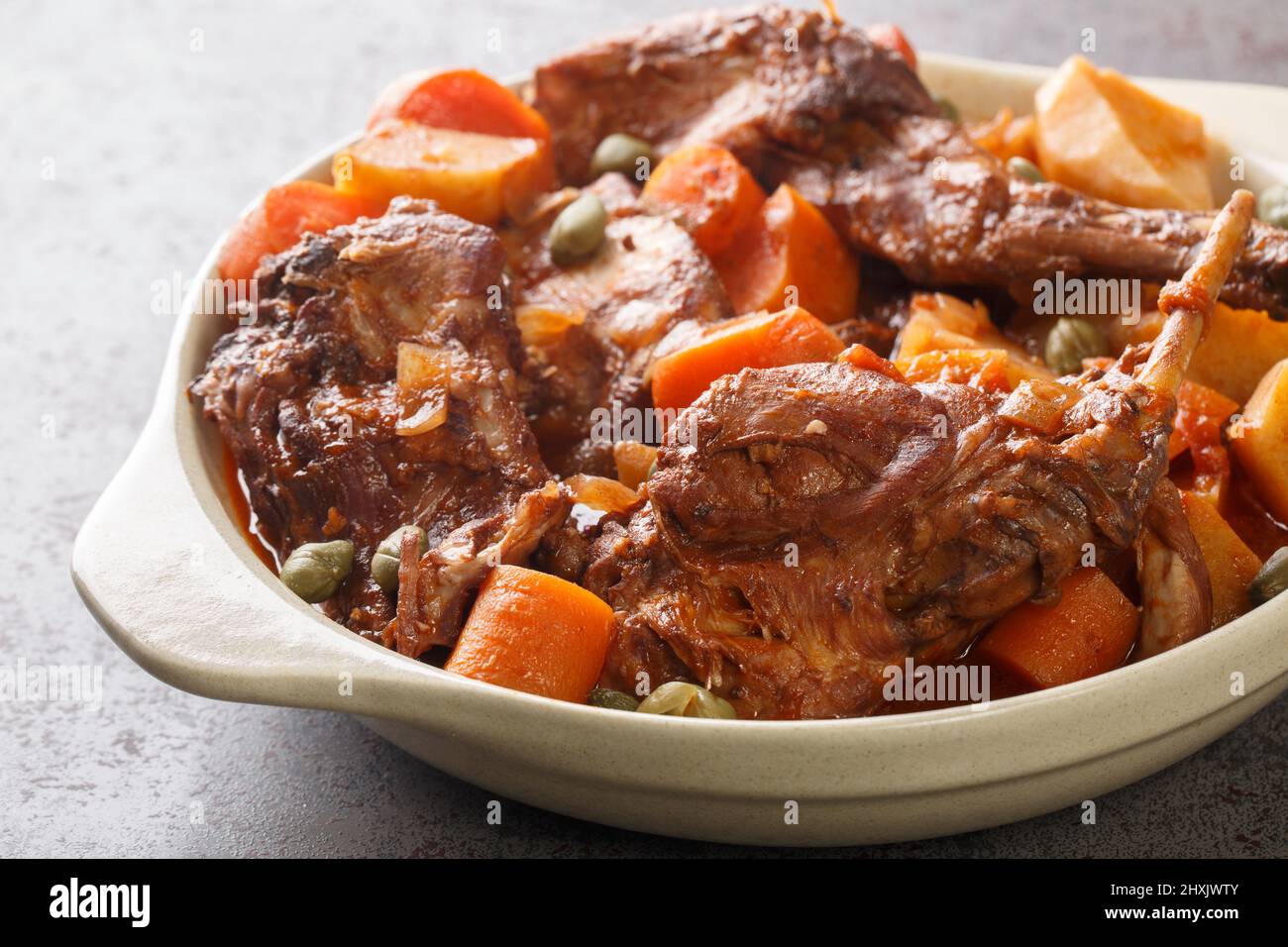 Fenkata dish of national Maltese cuisine cooked from rabbit meat with vegetables and gravy close-up in a saucepan on the table. horizontal Stock Photo