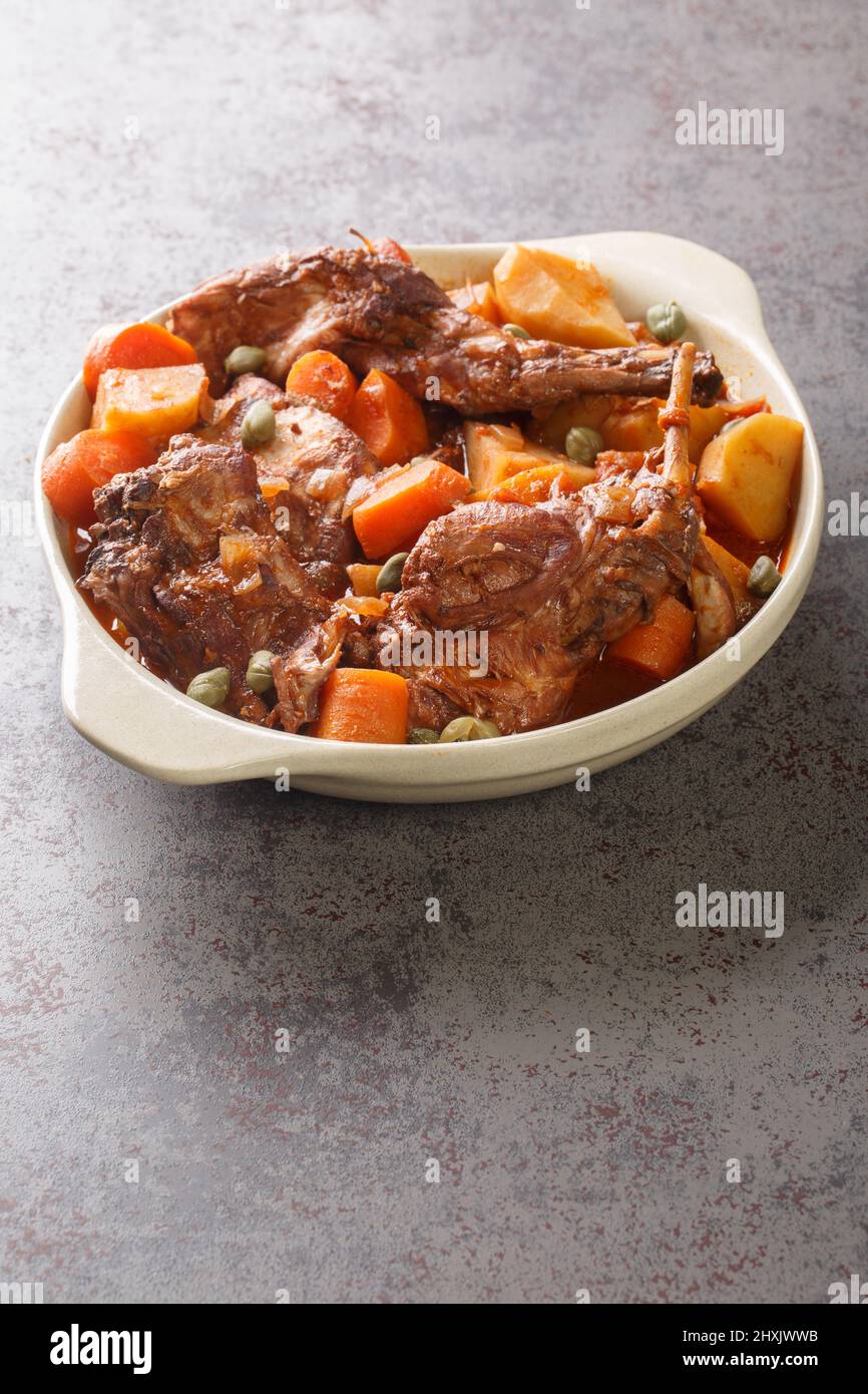 Traditional Malta national dish stewed rabbit Stuffat tal-Fenek closeup in the pan on the table. Vertical Stock Photo