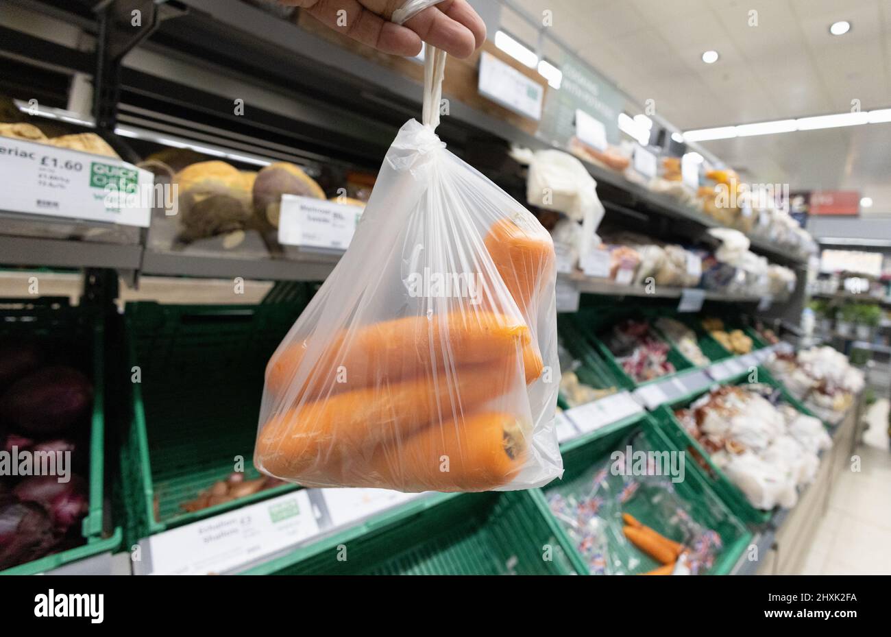 Buying supermarket carrots UK; Loose carrots in the supermarket vegetable aisle, example of basic or staple food, Waitrose veg aisle, Suffolk UK Stock Photo