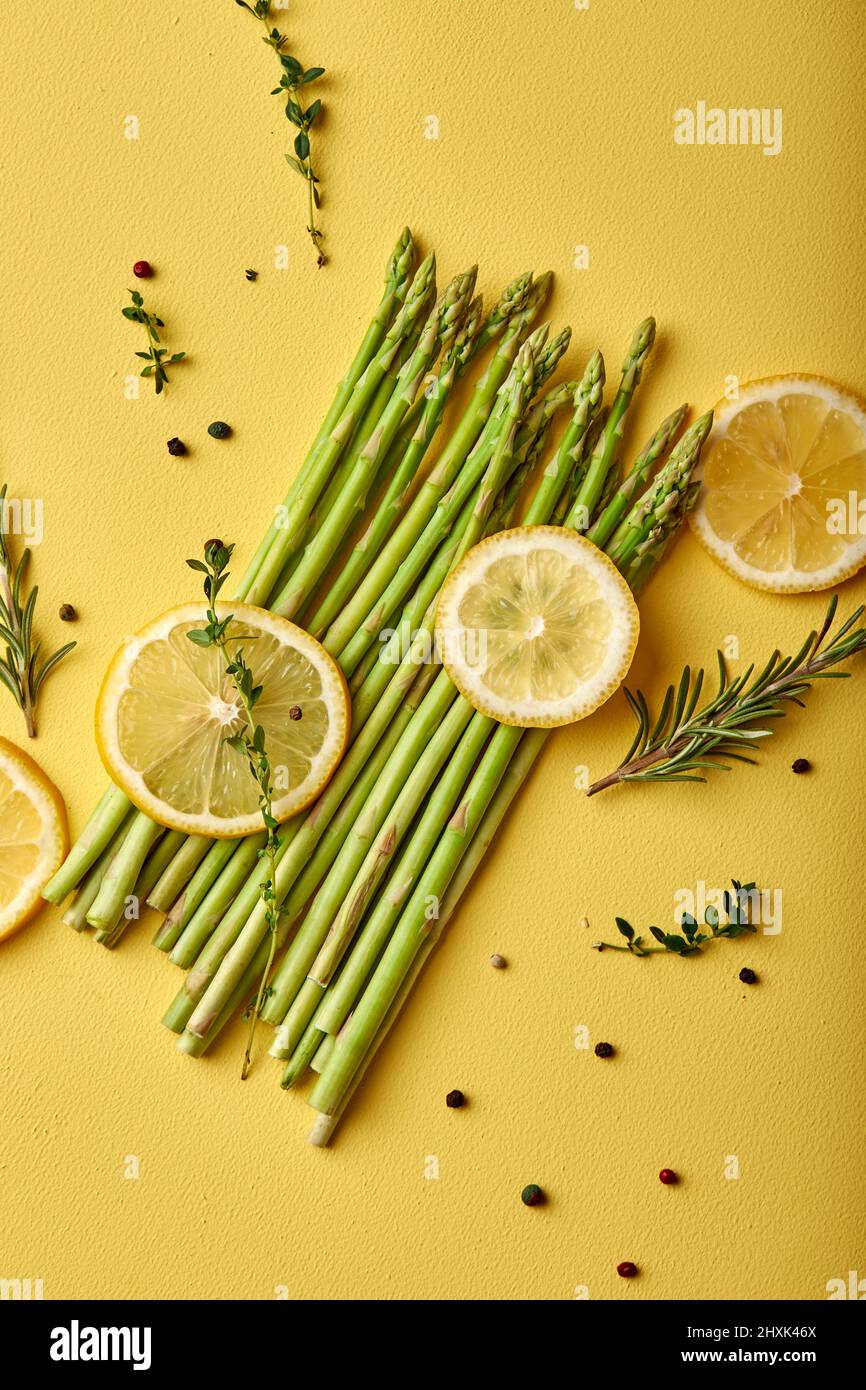 top view on Asparagus. fresh green asparagus close-up with slice of lemon isolated on yellow background. Healthy vegetarian food. flat lay, copy space Stock Photo