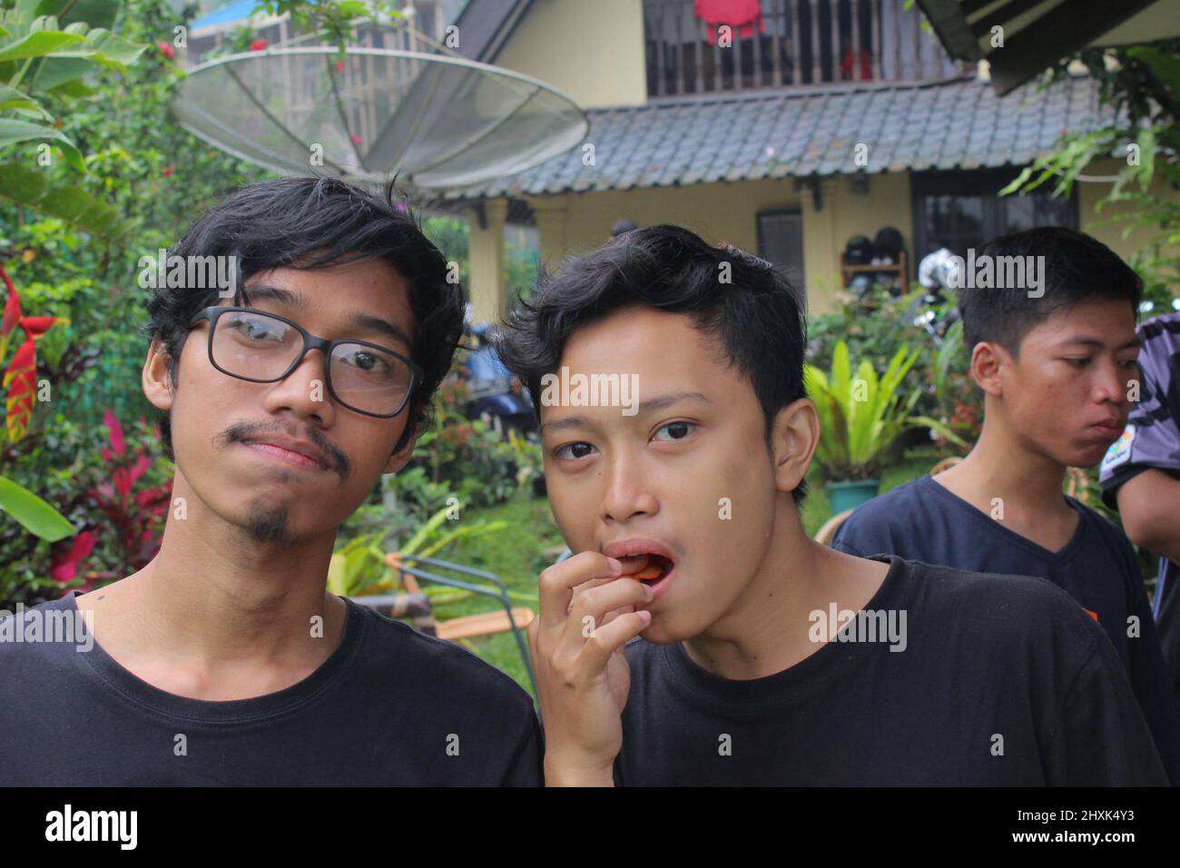Bogor, Indonesia - 12 24 2020: two men looking at the camera, the other one is eating a snack, the other has a serious face and the other is looking t Stock Photo