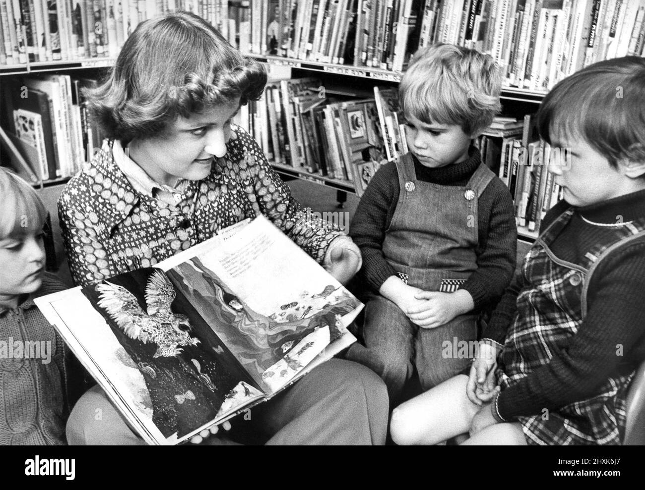 Library Assistant Christine Maley telling a story to Karen Miller, Mandy Baker and Gillian Bittlestone at Herrington Library in October 1977 Stock Photo