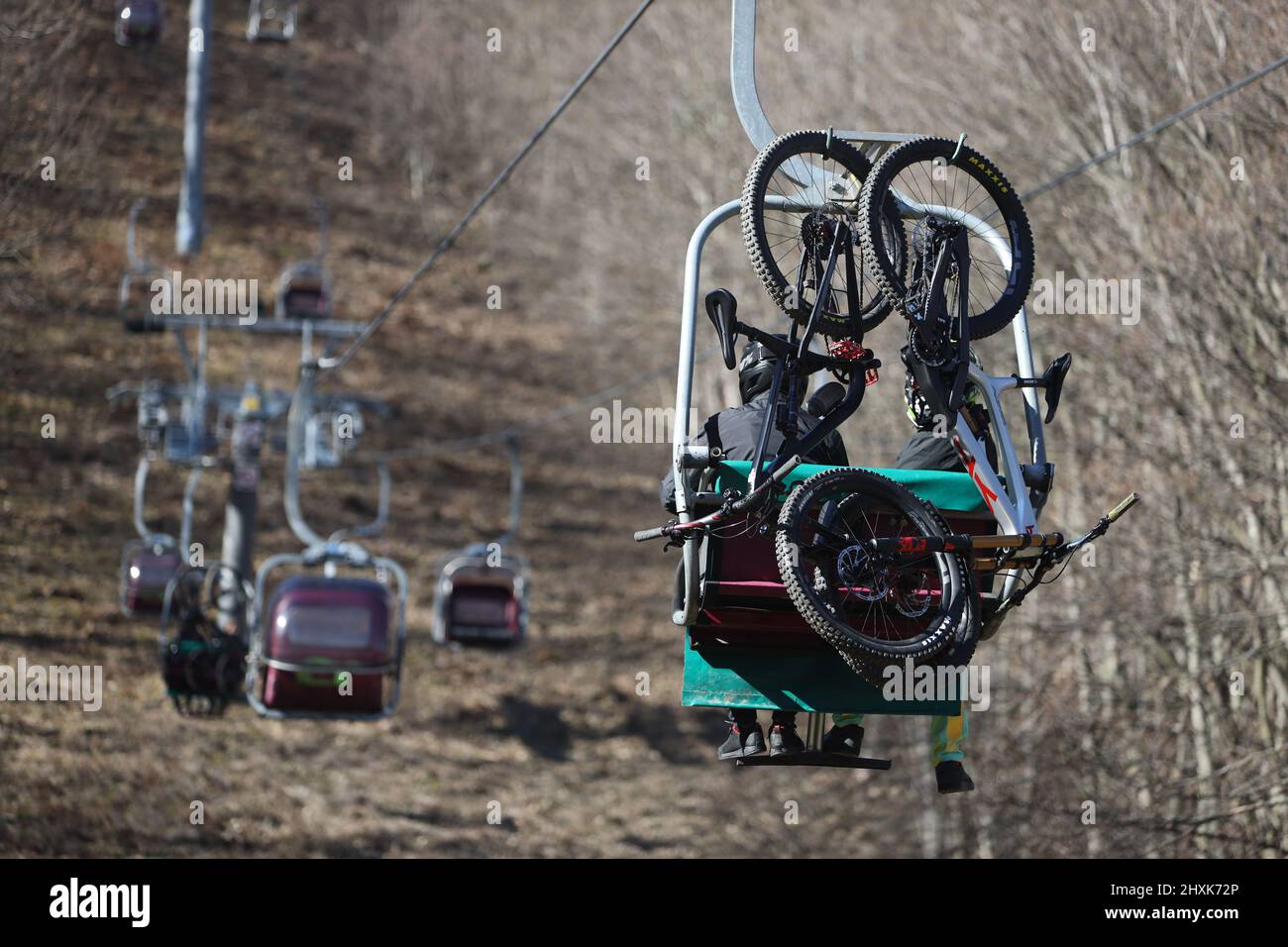 Thale, Germany. 13th Mar, 2022. Visitors ride their mountain bikes in the  chairlift to the Rosstrappe. From the top station there is a challenging  downhill track. The sunny weather again attracted many