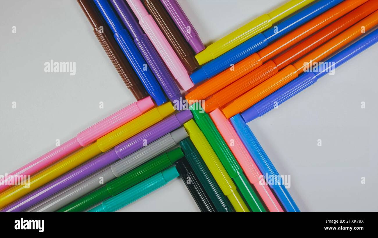 Many colored pencils are arranged around the edges of the image as a frame. In the center is an empty background with space for text. Mock up with copy space. Stock Photo