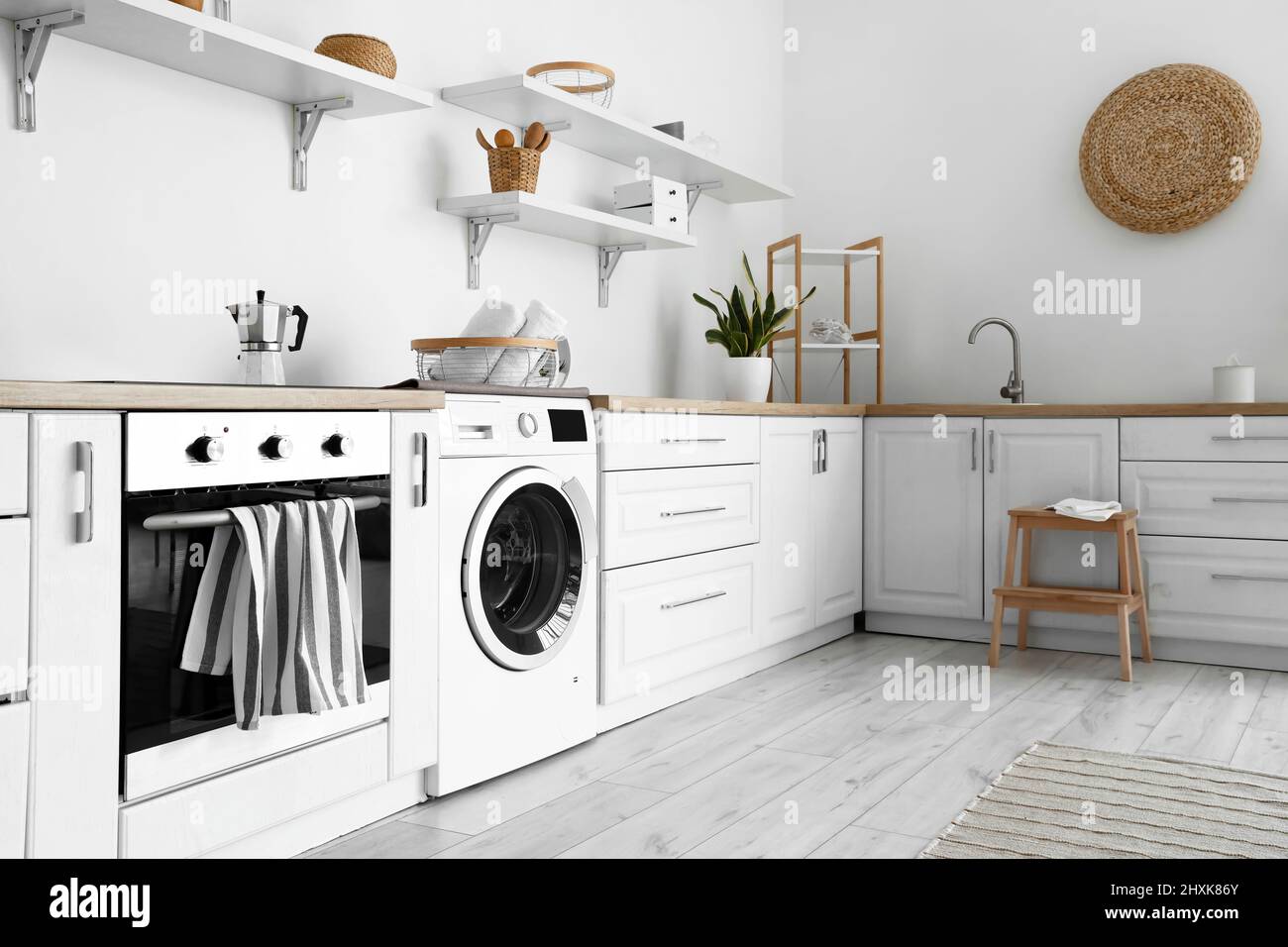 Interior of light kitchen with washing machine, oven and white counters ...