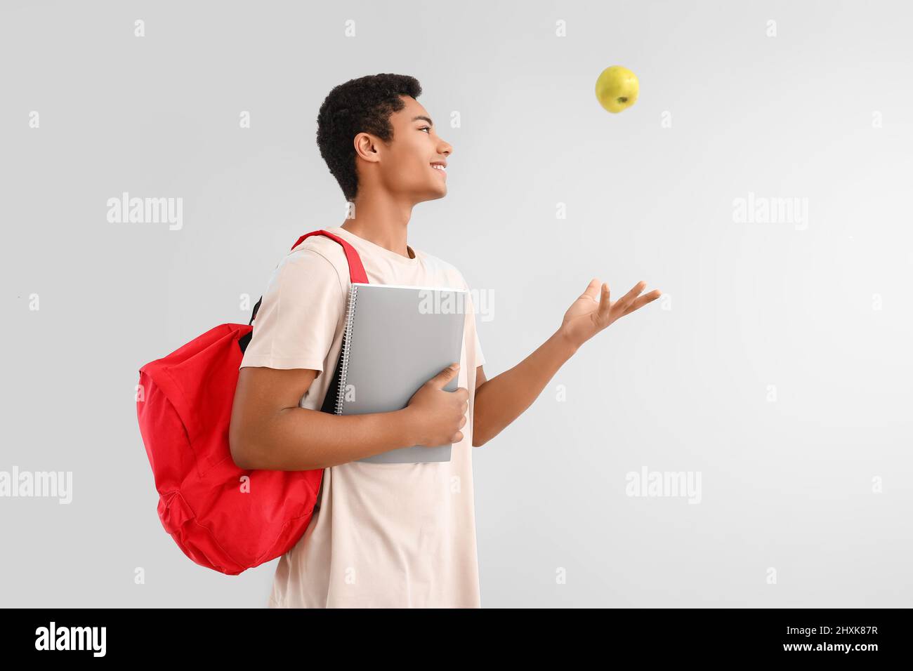 Male African-American student with notebook, backpack and apple on ...