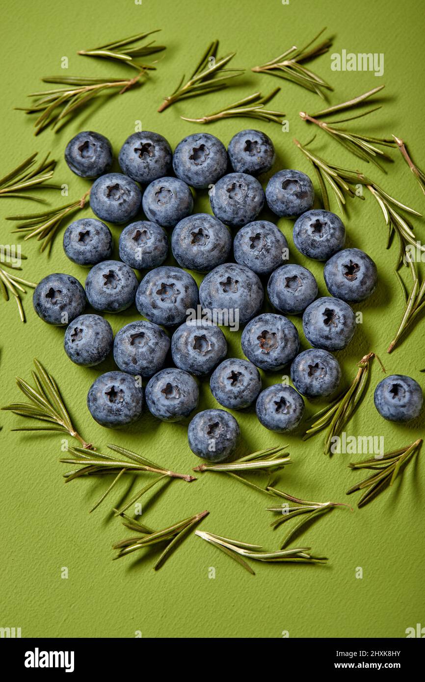 Fresh raw tasty blueberries with leaves isolated on green background, copy space. flat lay. fruits. Stock Photo