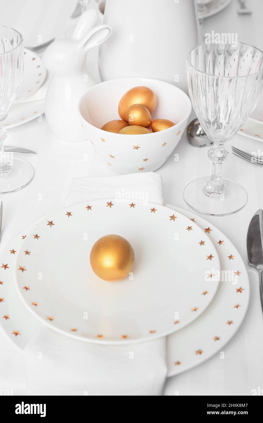 Beautiful table setting with golden Easter eggs in room, closeup Stock Photo