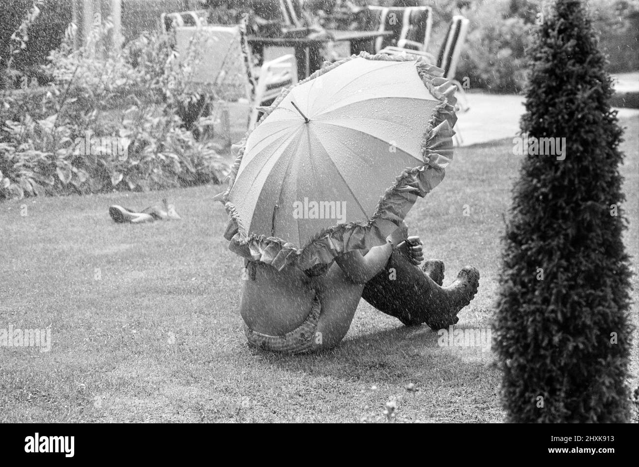 Hoping for a spot of rain to take her mind off the heatwave, this young lady, Jody, has to make do with the garden sprinkler to cool down, Reading, July 1976. Stock Photo