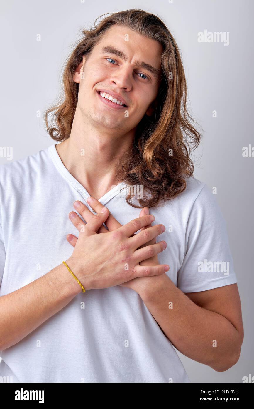 Happy smiling caucasian guy expressing gratitude, thankful for everything, keep hands on chest and looking at camera, isolated over light gray backgro Stock Photo