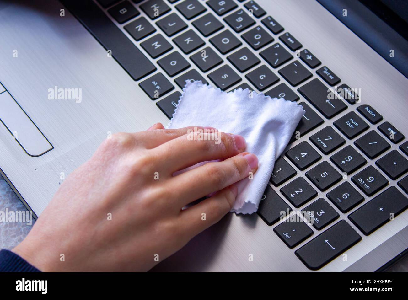 Woman cleaning laptop keyboard with a white cloth. Stock Photo