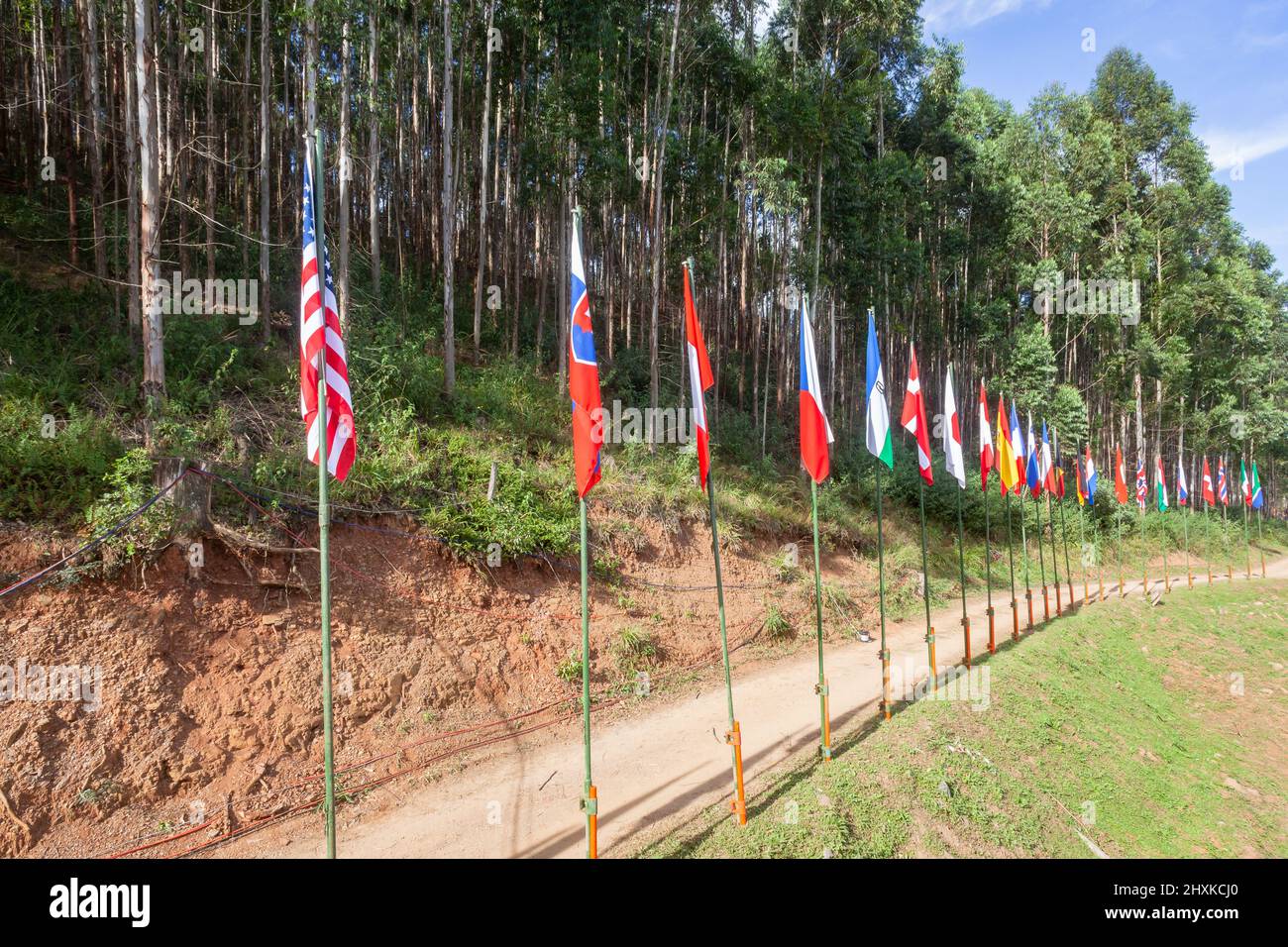 International cycling mountain mtb bike event with athlete cyclists flags of dozen countries on dirt track path at rural outdoor sporting location. Stock Photo