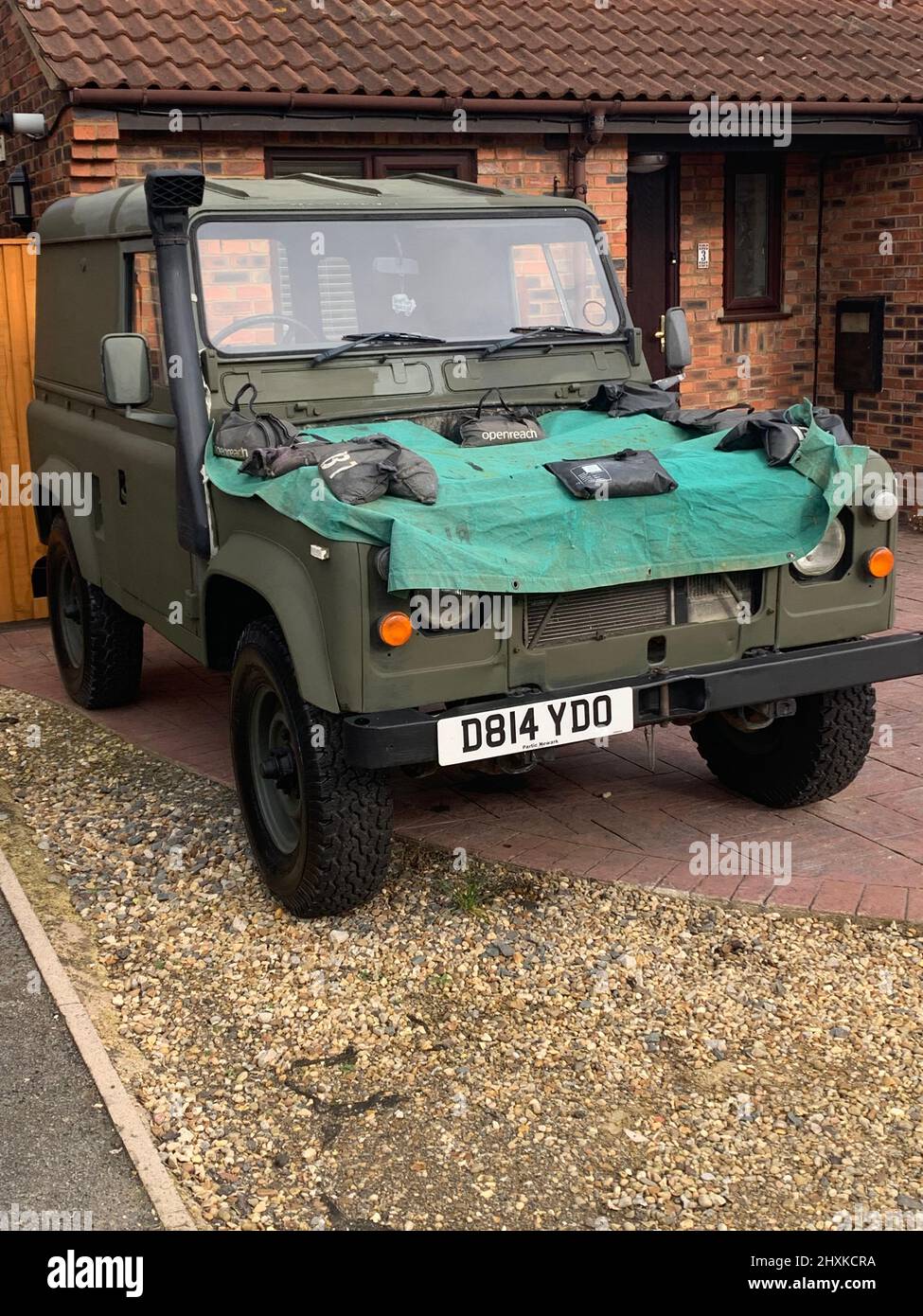 Military Land rover in green colours army colours with sheet on the front plastic Land Rover wolf defender ex military British Army Stock Photo