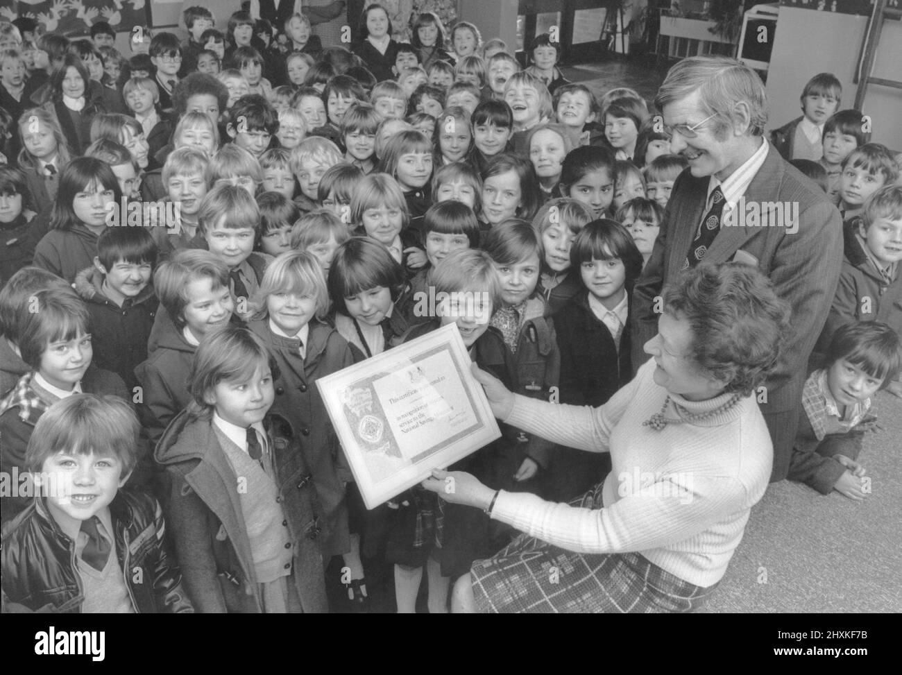The last presentation of the National Savings' jubilee year to a South Warwickshire school fell to Lillington C of E First School, Leamington.  In the photograph Mr Anthony Butcher and headmistress Miss J. Williams show the children the certificate to mark 69 years' contribution to the movement. 7th December 1976 Stock Photo