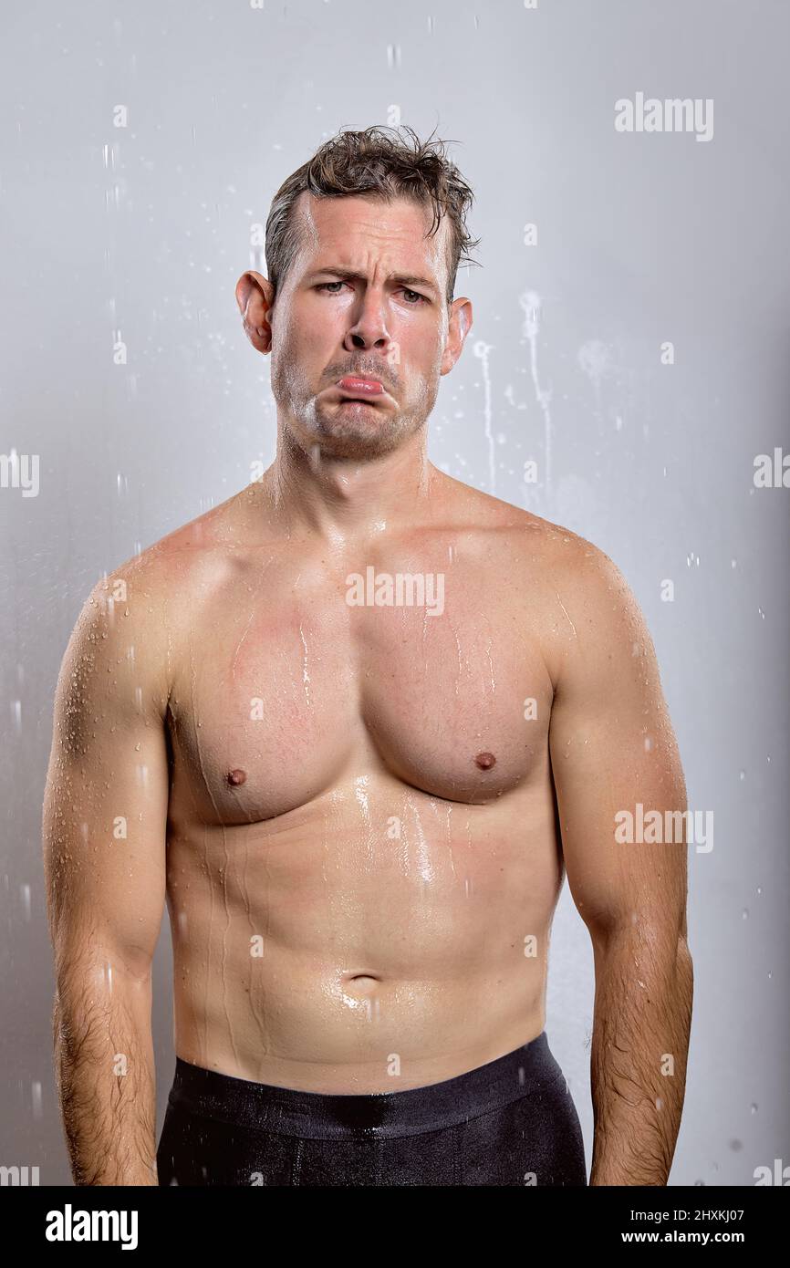 american young man taking shower in bathroom, relaxed man is upset, spending time in shower in the morning. handsome guy is dissatisfied with somethin Stock Photo