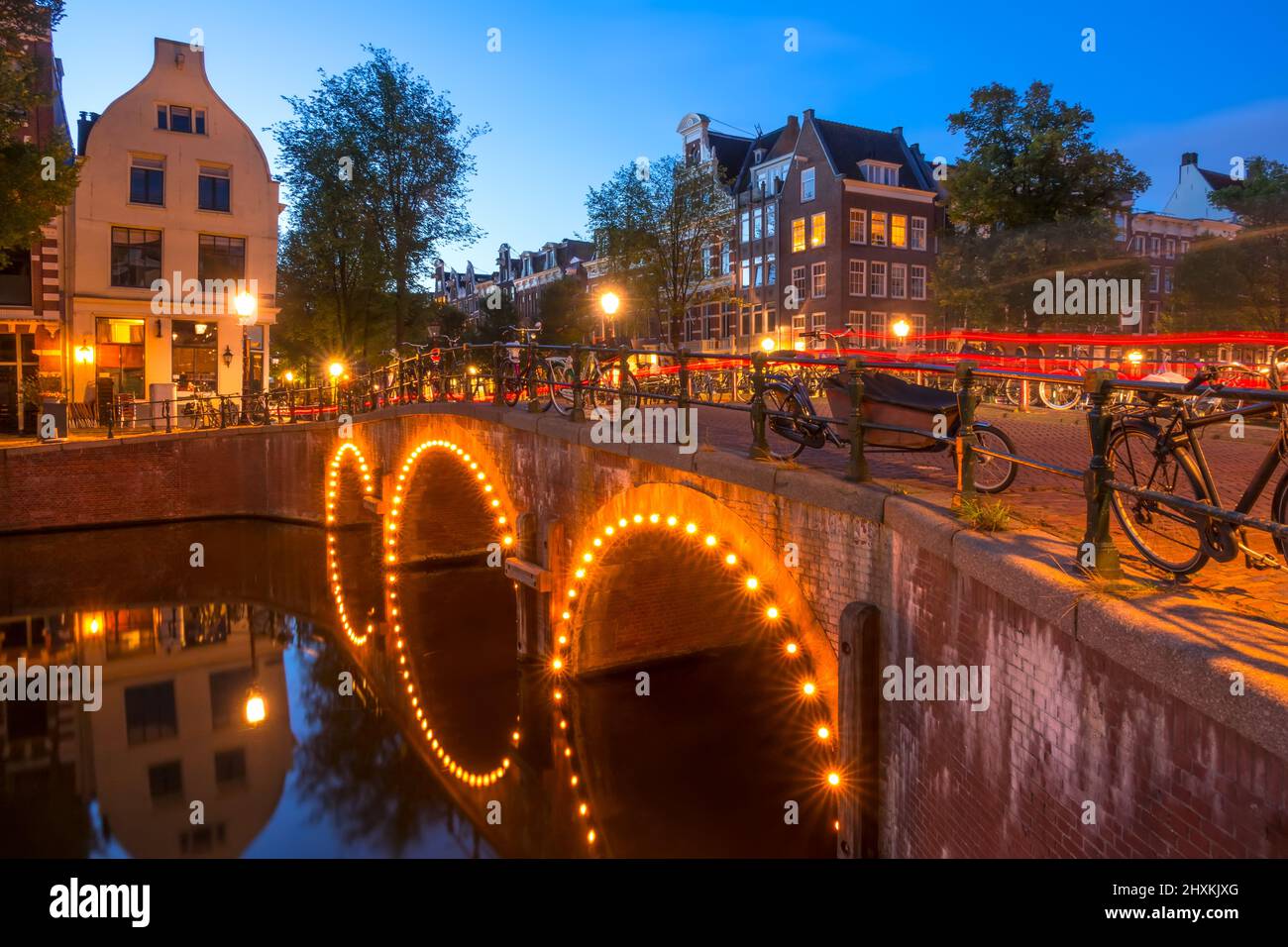 Netherlands. Stone bridge with three arches on the Amsterdam Canal. Lots of parked bikes. End of the night Stock Photo