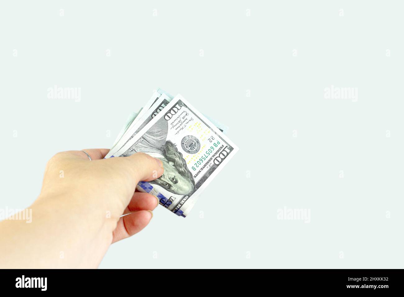 Hand giving money US dollars on grey background. Finance, earnings, crediting. Stock Photo