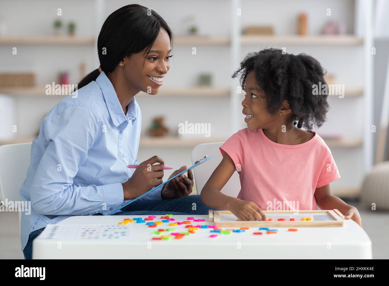 Cheerful child development specialist testing cute little girl Stock