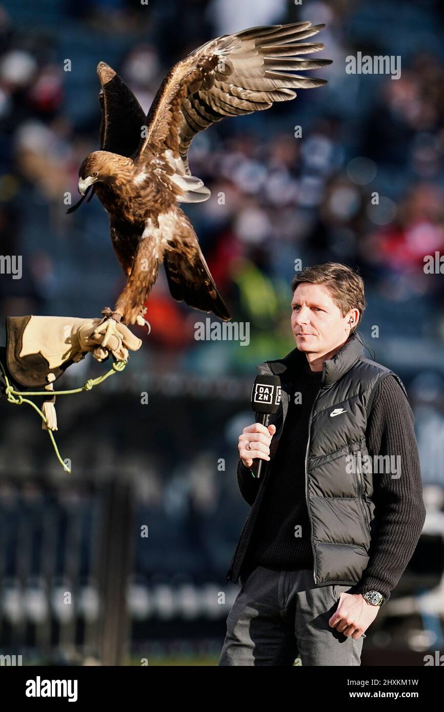 13 March 2022, Hessen, Frankfurt/Main: Soccer: Bundesliga, Eintracht Frankfurt - VfL Bochum, Matchday 26, Deutsche Bank Park. Frankfurt coach Oliver Glasner stands next to the golden eagle, Eintracht's mascot 'Attila,' during a television interview. Photo: Uwe Anspach/dpa - IMPORTANT NOTE: In accordance with the requirements of the DFL Deutsche Fußball Liga and the DFB Deutscher Fußball-Bund, it is prohibited to use or have used photographs taken in the stadium and/or of the match in the form of sequence pictures and/or video-like photo series. Stock Photo