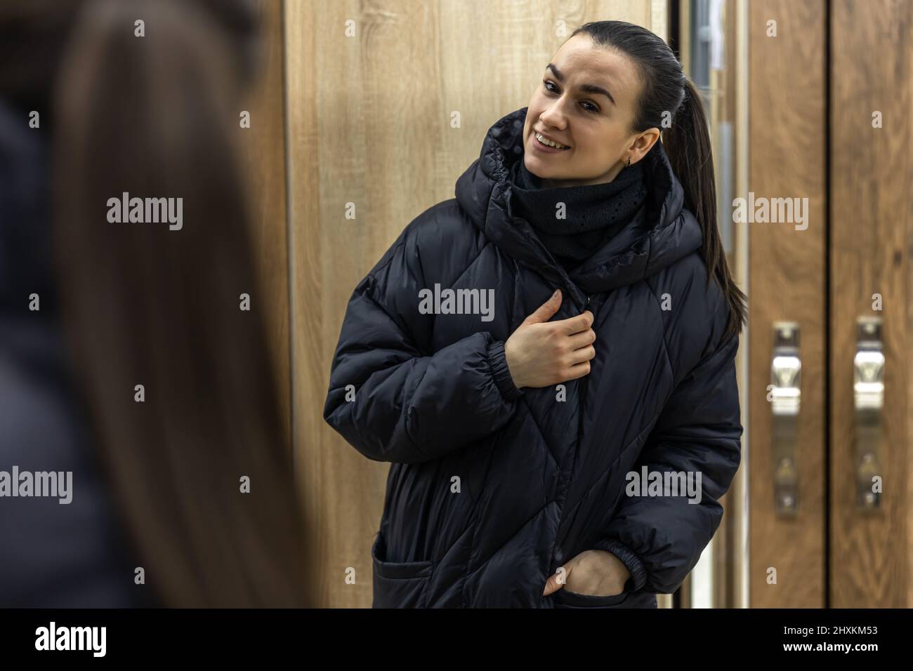 A young woman looks at herself in a closet mirror. Stock Photo