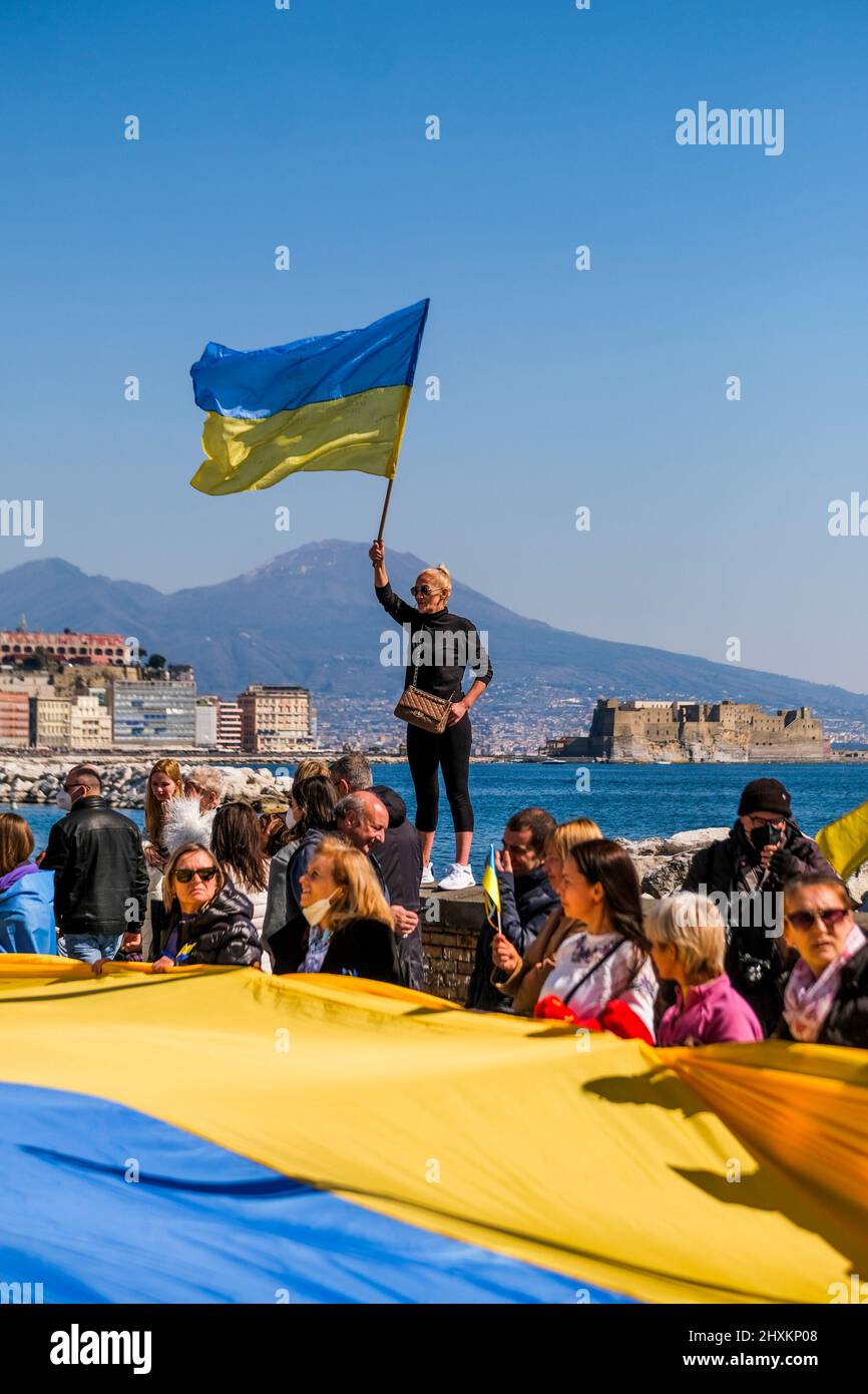 the ukrainian community in naples is today, 13 march 2022, holding a demonstration along the streets of naples on arrival at the american consulate, displaying a large ukrainian flag about fifty metres long, demanding that nato close the airspace in ukraine to prevent the bombing of cities by russia. Stock Photo