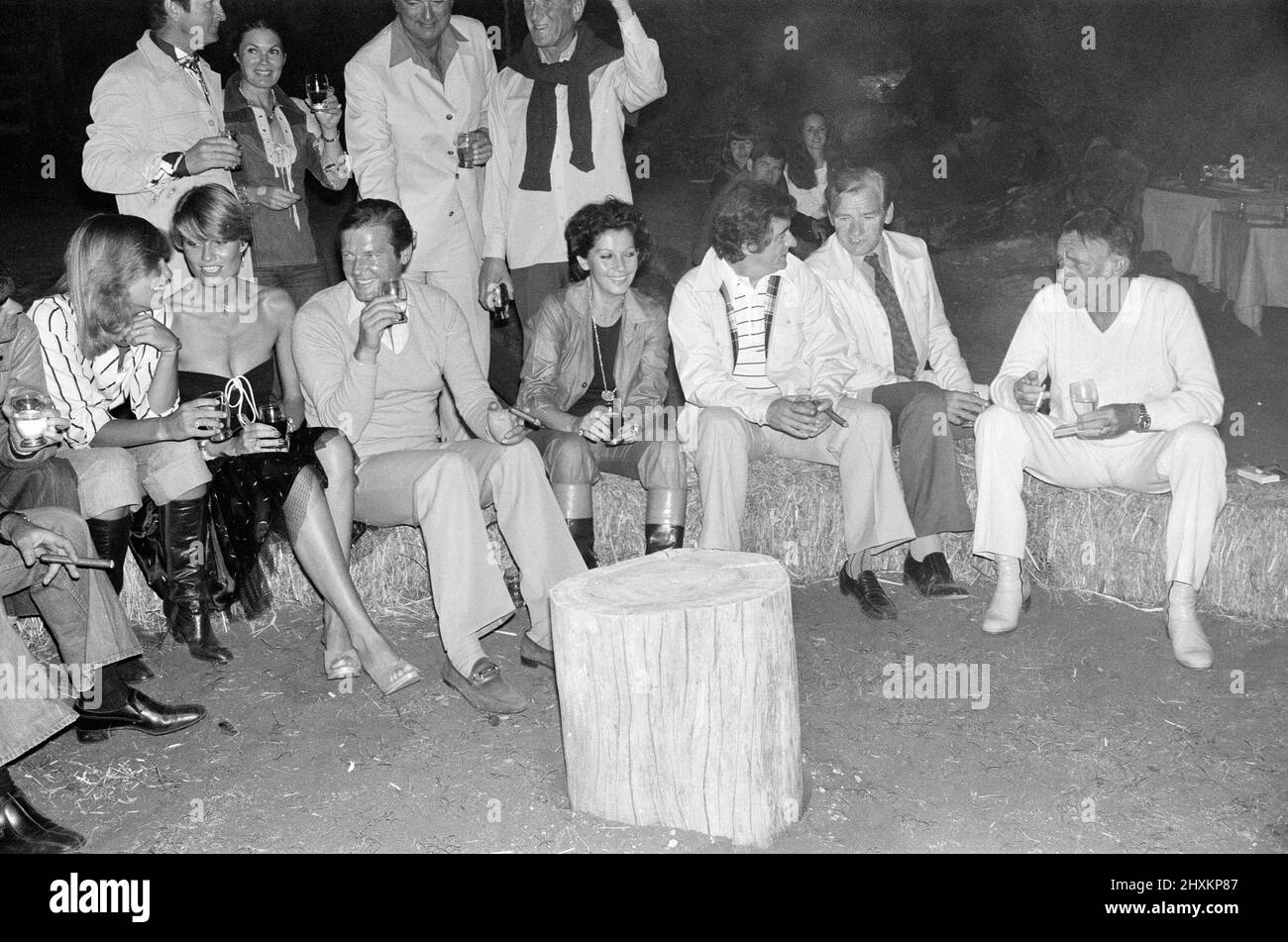 Roger Moore's 50th Birthday Party in the bush near Tshipise, South Africa, during the filming of his latest film 'Wild Geese.' Suzy Miller, Roger Moore, Luisa Mattioli, Richard Burton and other party guests. 18th October 1977. Stock Photo
