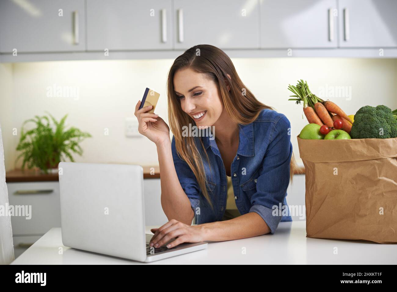 I can get everything delivered to my door. Cropped shot of a young woman doing some online shopping with her groceries beside her. Stock Photo