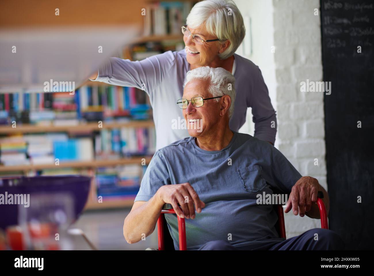 Nothing gets us down. Shot of a senior woman pushing her husband in a wheelchair at home. Stock Photo