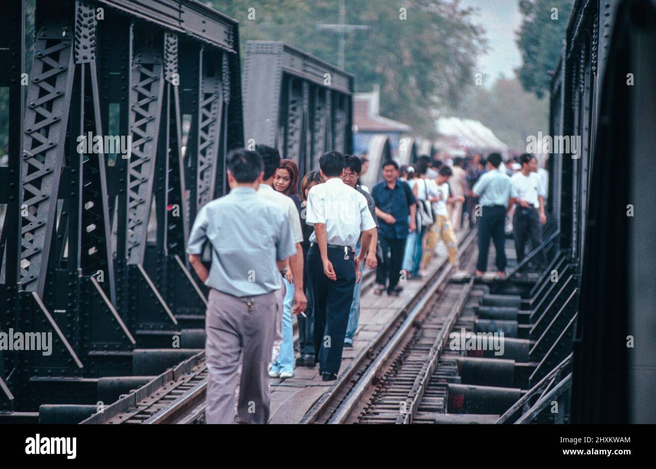 Every day thousands of tourists cross the famous River Kwai Bridge at Kanchanaburi by train and on foot. Stock Photo