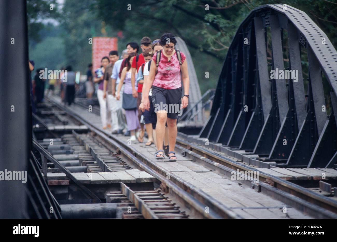 Every day thousands of tourists cross the famous River Kwai Bridge at Kanchanaburi by train and on foot. Stock Photo