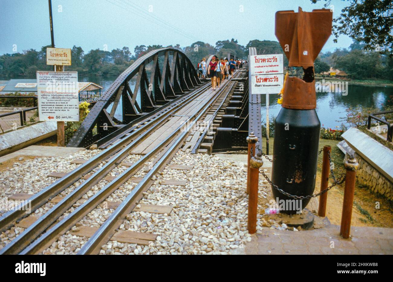 An Allied aircraft bomb marks the Eastern approach: Every day thousands of tourists cross the famous River Kwai Bridge at Kanchanaburi by train and on foot. Stock Photo