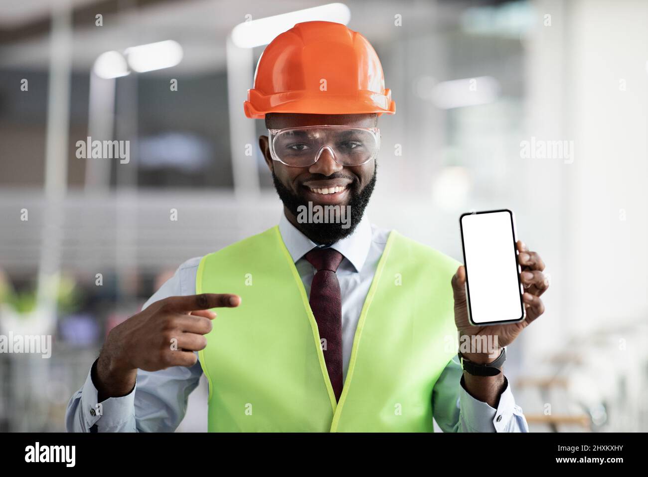 Happy african american architect pointing at smartphone with empty screen Stock Photo