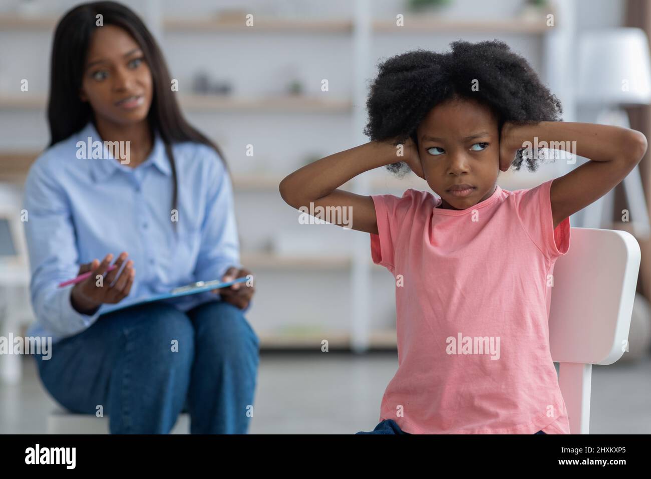 Unruly little girl covering her ears and looking aside Stock Photo
